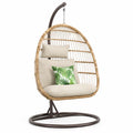 Sedia sospesa in rattan con cuscini beige e struttura in acciaio